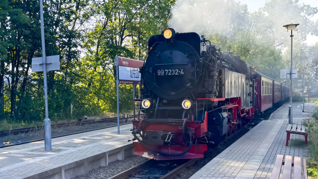 Eine Dampflok der Harzerschmalspurbahnen steht dampfend im Bahnhof Ilfeld.