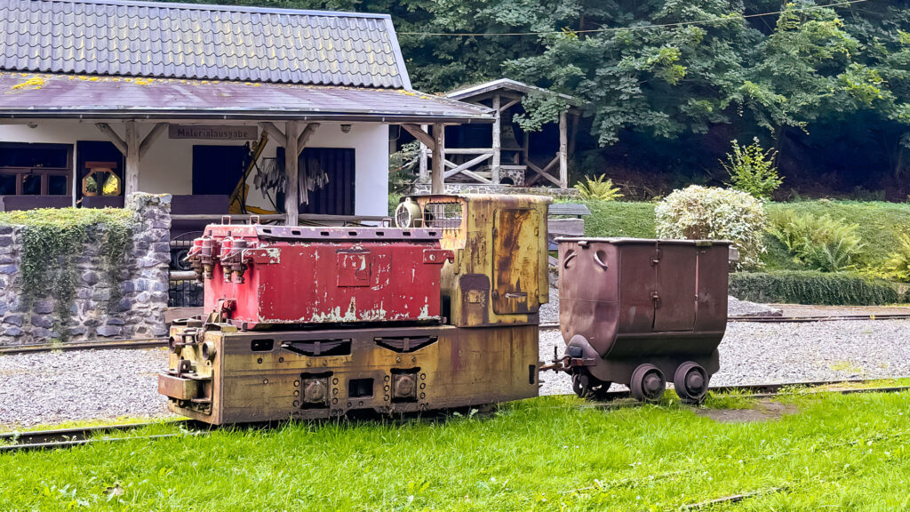 Eine alte Grubenlok steht vor einem Haus, das zum Besucherbergwerk Rabensteiner Stollen gehört.