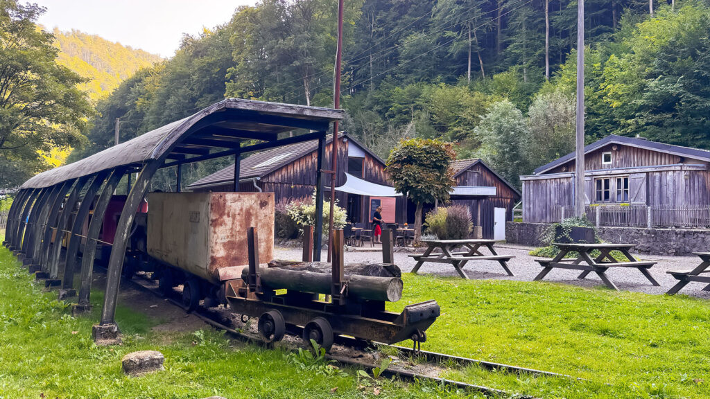 Eine alte Grubenlok steht vor einem Haus, das zum Besucherbergwerk Rabensteiner Stollen gehört.