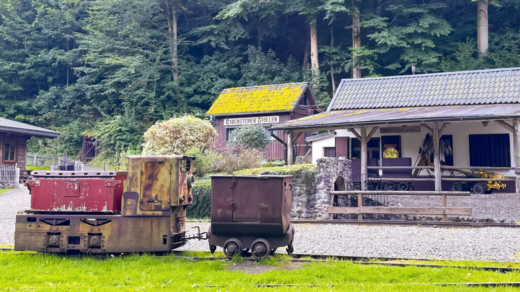 Eine alte Grubenlok steht vor einem Haus, das zum Besucherbergwerk Rabensteiner Stollen gehört.