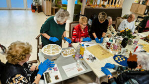 Ältere Menschen sitzen um einen weihnachtlich geschmückten Tisch und backen Plätzchen