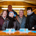 Fünf Frauen und Männer in einer Holzhütte auf dem Weihnachtsmarkt.