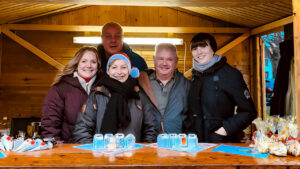 Fünf Frauen und Männer in einer Holzhütte auf dem Weihnachtsmarkt.