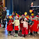 Ein weihnachtlicher Kinderchor tritt auf in einem Saal.