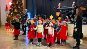 Ein weihnachtlicher Kinderchor tritt auf in einem Saal.