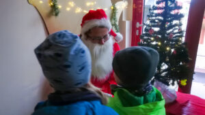 Zwei Kinder stehen vor dem Weihnachtsmann.