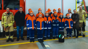 Gruppenbild von jungen Feuerwehrleuten mit zwei erwachsenen Ausbildern sowie einem Mann in Zivilkleidung