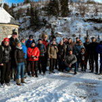 Männer und Frauen im mittleren Alter auf der schneebedeckten Staumauer der Neustädter Talsperre, links ist etwas vom Wasser zu sehen.