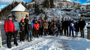 Männer und Frauen im mittleren Alter auf der schneebedeckten Staumauer der Neustädter Talsperre, links ist etwas vom Wasser zu sehen.