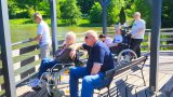 Bewohner und Pfleger, Männer und Frauen, der Diakonie Tagespflege an einem Teich auf einem hölzernen Aussichtsdeck